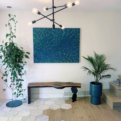 Pothos and palm styling in a modern entryway with a live-edge bench.