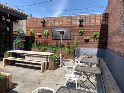 Outdoor restaurant patio with planter boxes and string lights.